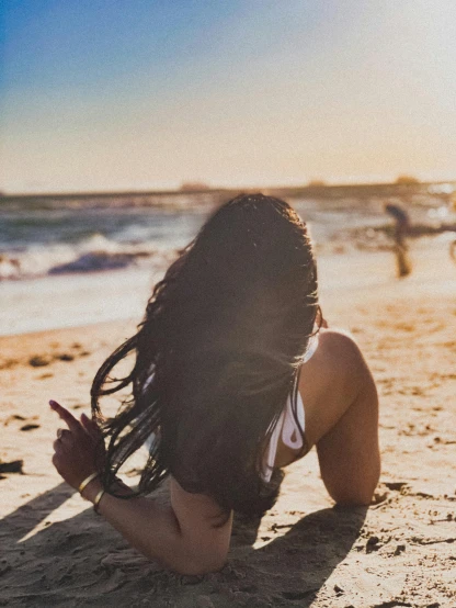 a woman laying on top of a sandy beach, pexels contest winner, profile image, girl with black hair, the sun at their back, half image