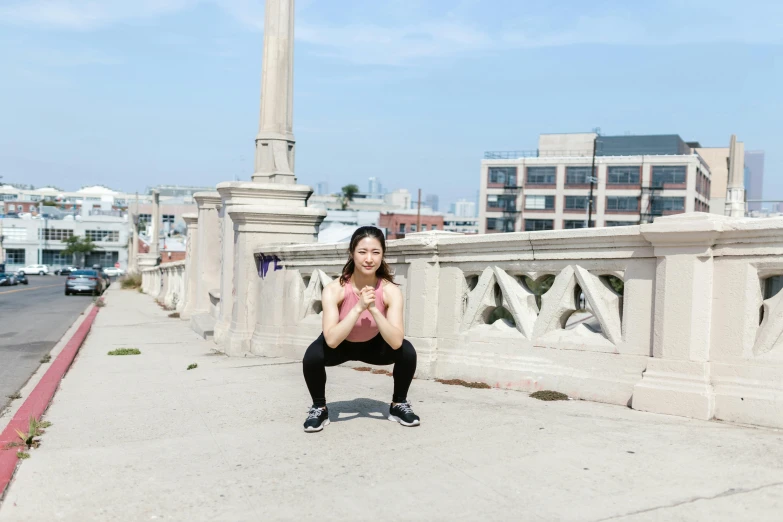 a woman squatting on a sidewalk with a city in the background, gemma chen, dim dingy gym, profile image, bridges