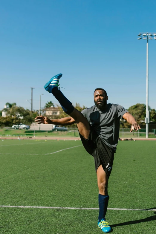 a man kicking a soccer ball on a field, dynamic stretching, maximus jacobs, square, oceanside