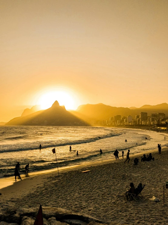 a group of people standing on top of a sandy beach, cristo redentor, which shows a beach at sunset, sun drenched, today\'s featured photograph 4k