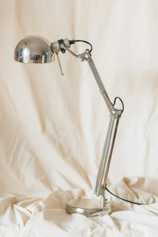 a desk lamp sitting on top of a bed, by Gawen Hamilton, unsplash, kinetic art, silver insect legs, 1920s studio lighting, mechanical arm, perfect crisp sunlight