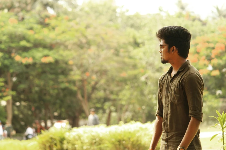 a man walking through a lush green park, by Max Dauthendey, pexels contest winner, realism, handsome girl, movie frame still, looking to his side, at college