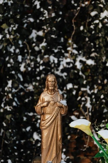 a statue of jesus surrounded by flowers in the snow, a statue, unsplash, beautiful gold saint, hearts, 3 5 mm photo, garden