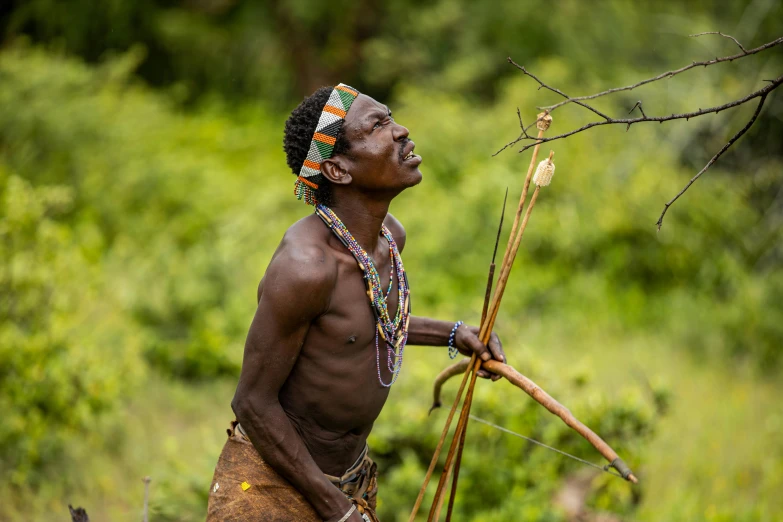 a man that is standing in the grass with a stick, intricate african jewellery, heroic shooting bow pose, thumbnail, keter class