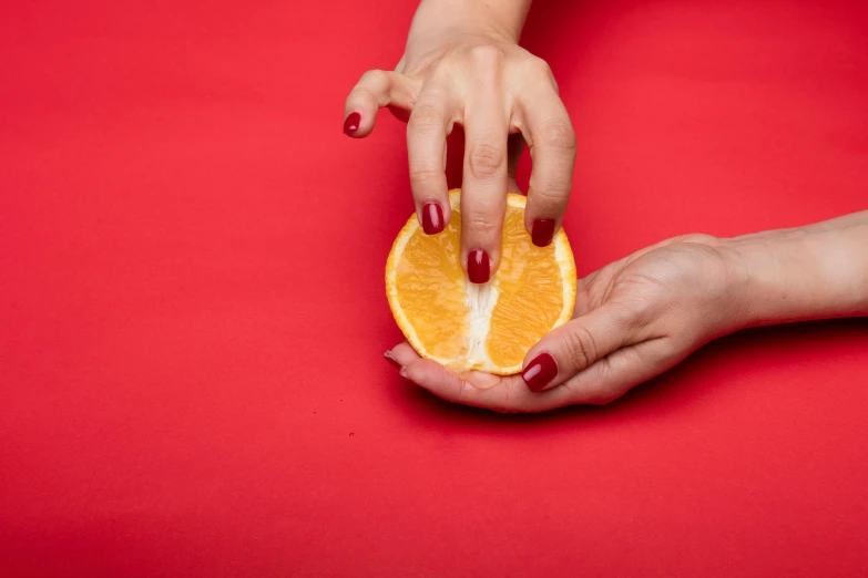 a close up of a person holding an orange, by Julia Pishtar, magic realism, coloured gel studio light, wolfy nail, one is red, hands on counter