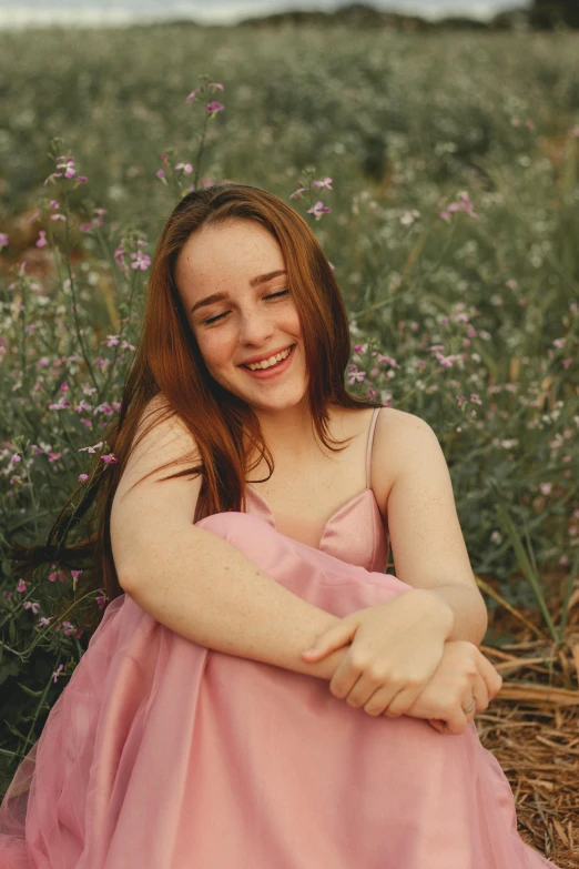 a woman in a pink dress sitting in a field, soft flawless pale skin, smiling down from above, teenage girl, uploaded