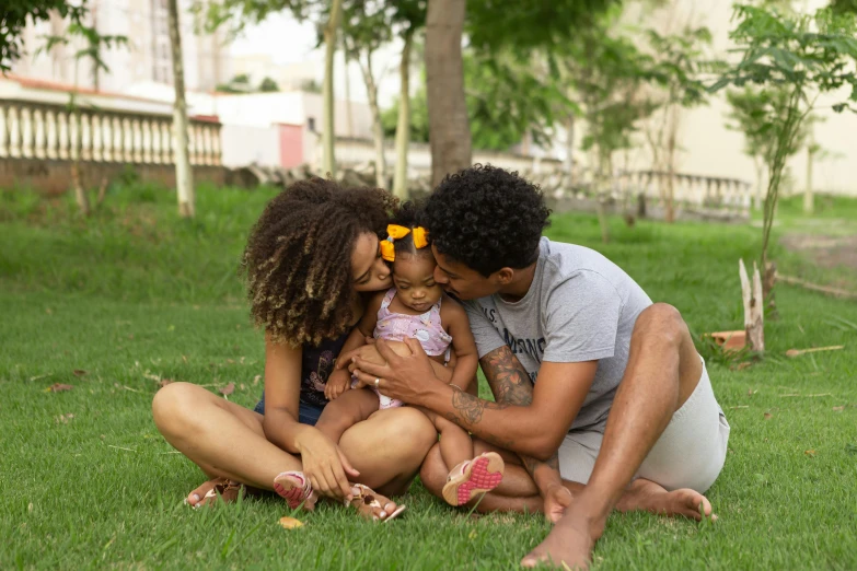 a man and woman sitting in the grass with a baby, by Almada Negreiros, pexels, renaissance, with afro, in sao paulo, daughter, couple kissing