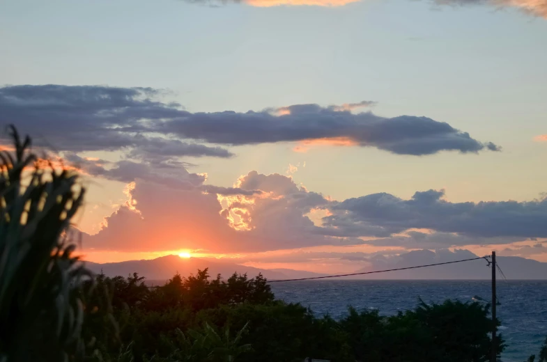 a view of the sun setting over the ocean, a picture, unsplash, romanticism, okinawa japan, shot from roofline, agrigento, distant mountains lights photo