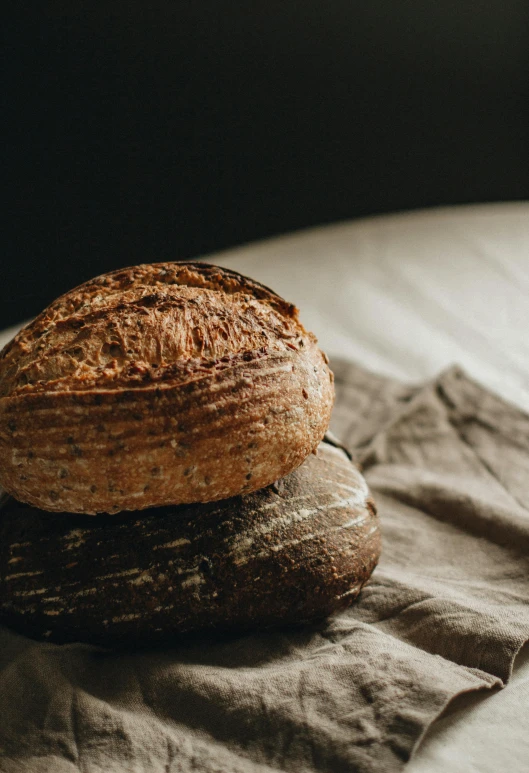 a loaf of bread sitting on top of a table, a portrait, unsplash, a pair of ribbed, mineral grains, beautifully lit, large tall