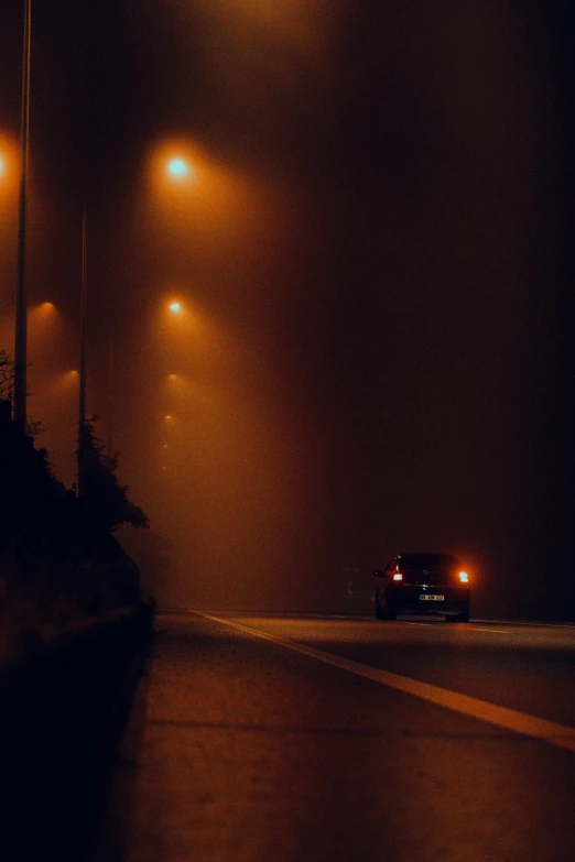 a car driving down a street at night, pexels contest winner, romanticism, volumetric fog and haze, car on highway, orange fog, streetlight at night