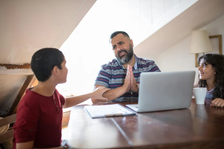 a group of people sitting around a table with a laptop, fatherly, thumbnail, te pae, reassuring