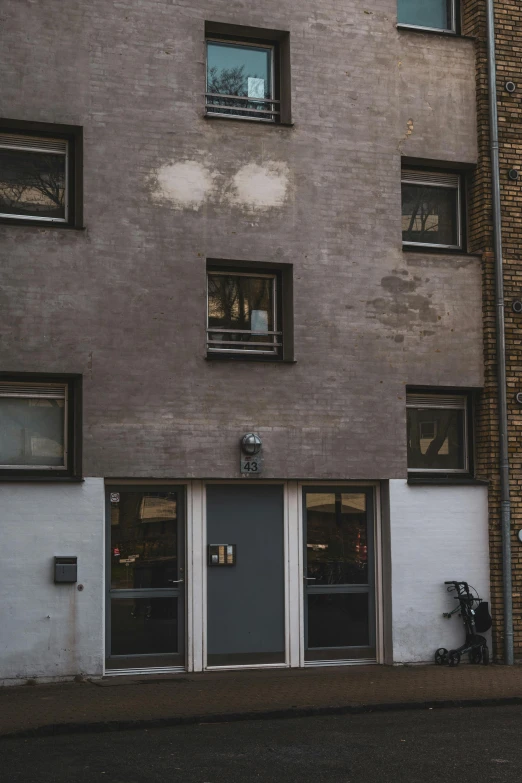 a person riding a skateboard on a city street, a photo, by Nina Hamnett, unsplash, postminimalism, doors to various living quarters, gray stone wall, kreuzberg, low quality photo