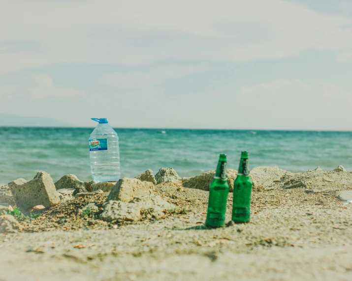 a couple of bottles sitting on top of a sandy beach