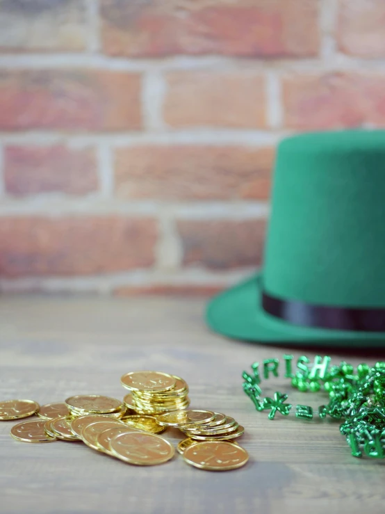 a green hat sitting on top of a wooden table, by Sylvia Wishart, pexels contest winner, gold coins, holiday, irish, lgbtq