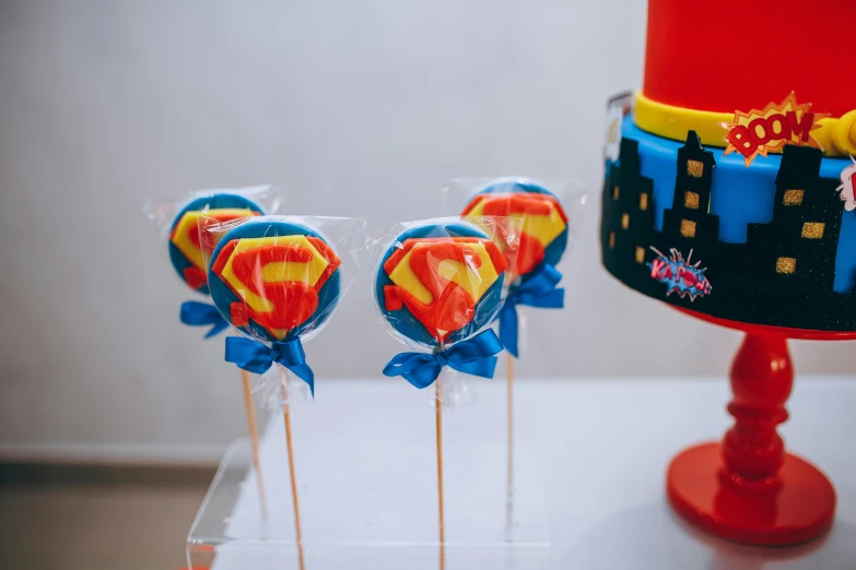 a couple of lollipops sitting on top of a table, superman, profile image, birthday party, trending photo