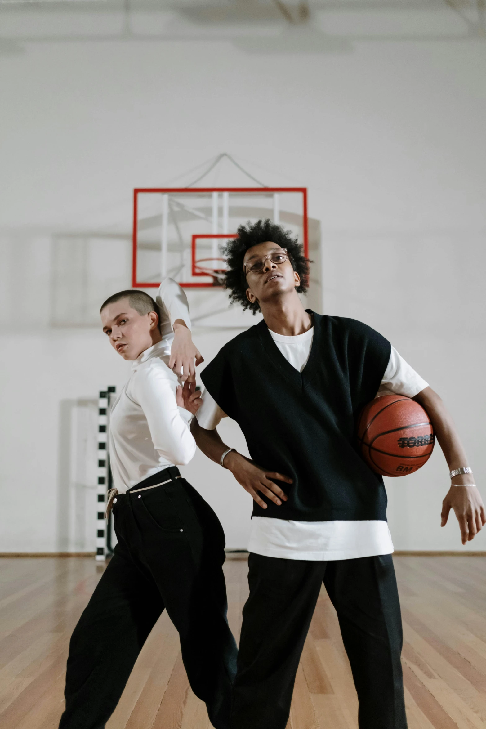 a couple of people playing a game of basketball, an album cover, trending on dribble, antipodeans, medium shot portrait, performing a music video, white and black clothing, androgynous