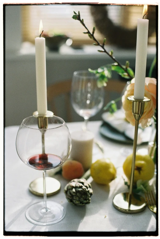 a couple of candles sitting on top of a table, wine glass, julia sarda, botanicals, creterion collection