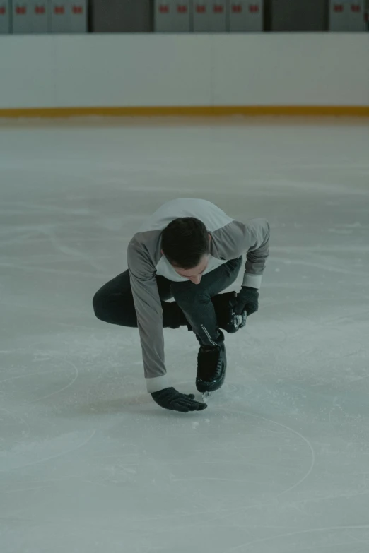 a man bending over to pick up something on the ice, unsplash, arabesque, still from the movie, andrea savchenko, injured, belgium