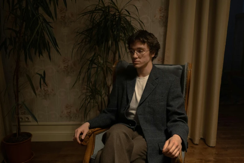 a man sitting in a chair in a room, an album cover, inspired by Jean Malouel, pexels contest winner, hyperrealism, clothed in ancient suit, stranger things character, anato finnstark. 5 0 mm, young adult male