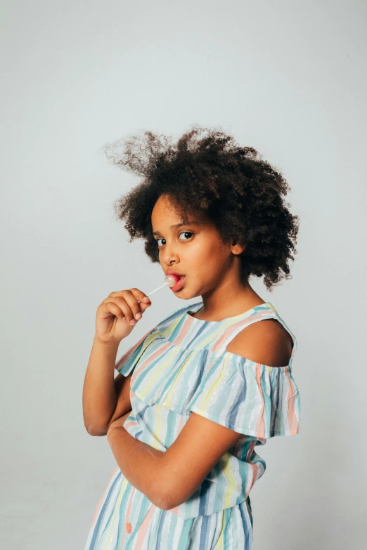 a little girl that is posing for a picture, long afro hair, wearing stripe shirt, non binary model, stockphoto