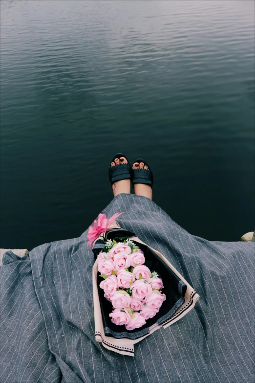 a person standing on a dock with flowers in their pants, a picture, trending on unsplash, roses in her hair, wearing a grey robe, pov photo, sitting
