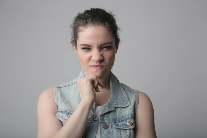 a woman in a denim vest posing for a picture, trending on pexels, sad grumpy face, pleading face, powerful chin, fighting pose