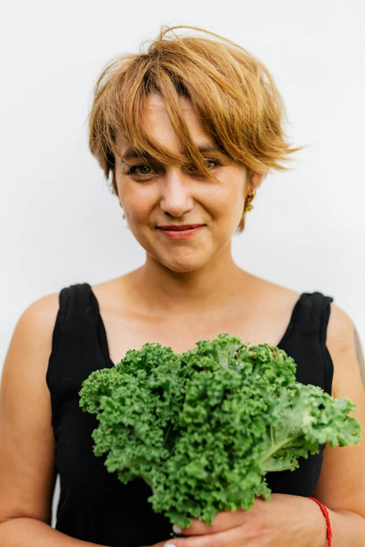 a woman holding a bunch of lettuce in her hands, an album cover, by Kristin Nelson, trending on unsplash, ana de la reguera portrait, with broccoli hair, portrait of kim wexler, she is wearing a black tank top