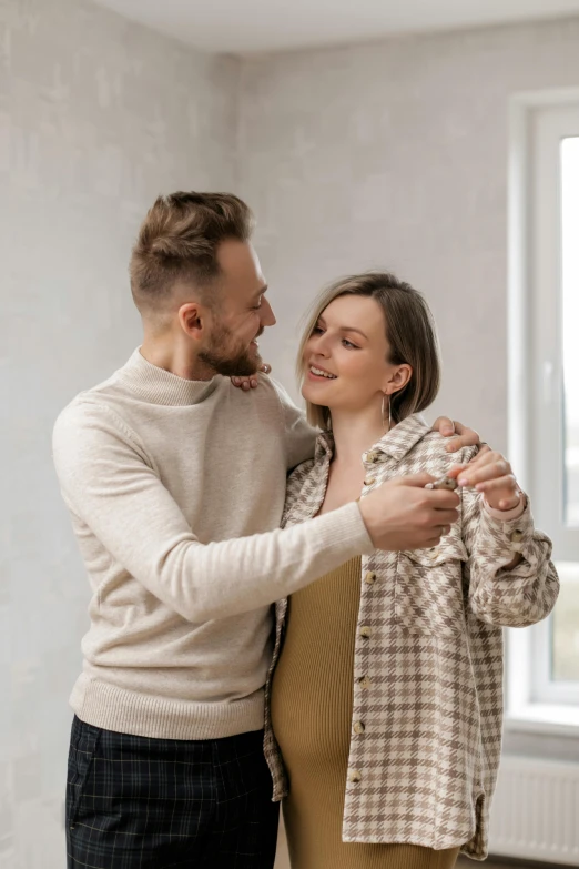 a man standing next to a woman in a room, a colorized photo, pexels contest winner, pair of keys, dancing with each other, wholesome, plain background