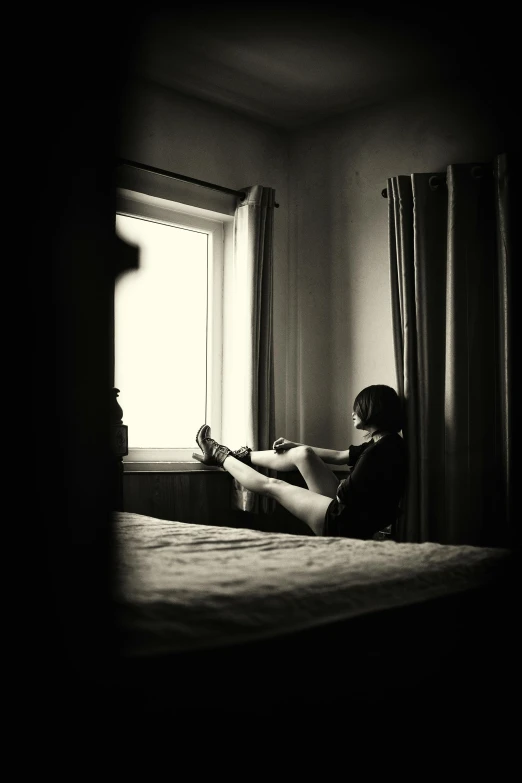 a person sitting on a bed in a dark room, a black and white photo, art photography, boy staring at the window, photograph”