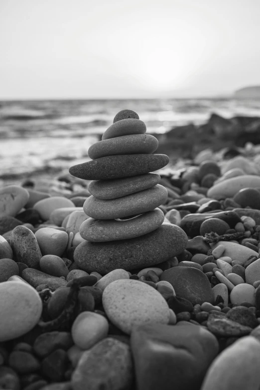 a pile of rocks sitting on top of a rocky beach, a black and white photo, unsplash, minimalism, yoga, ((rocks)), music album art, street photo