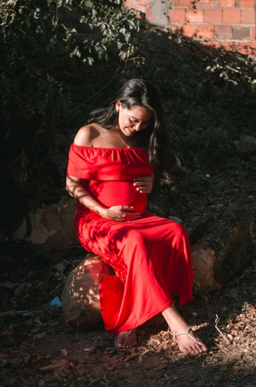 a woman in a red dress sitting on a rock, third trimester, in long dresses, profile image, chilean