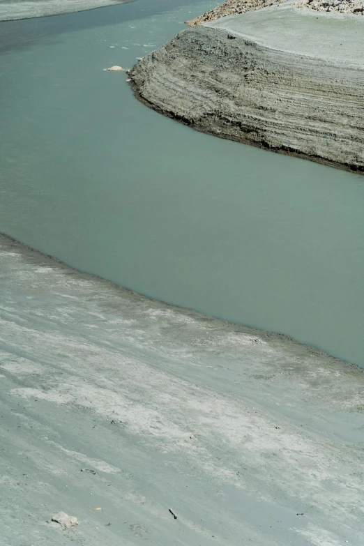 a man riding on the back of a horse next to a body of water, inspired by Andreas Gursky, minimalism, blue glacier, erosion channels river, colour photograph, overview