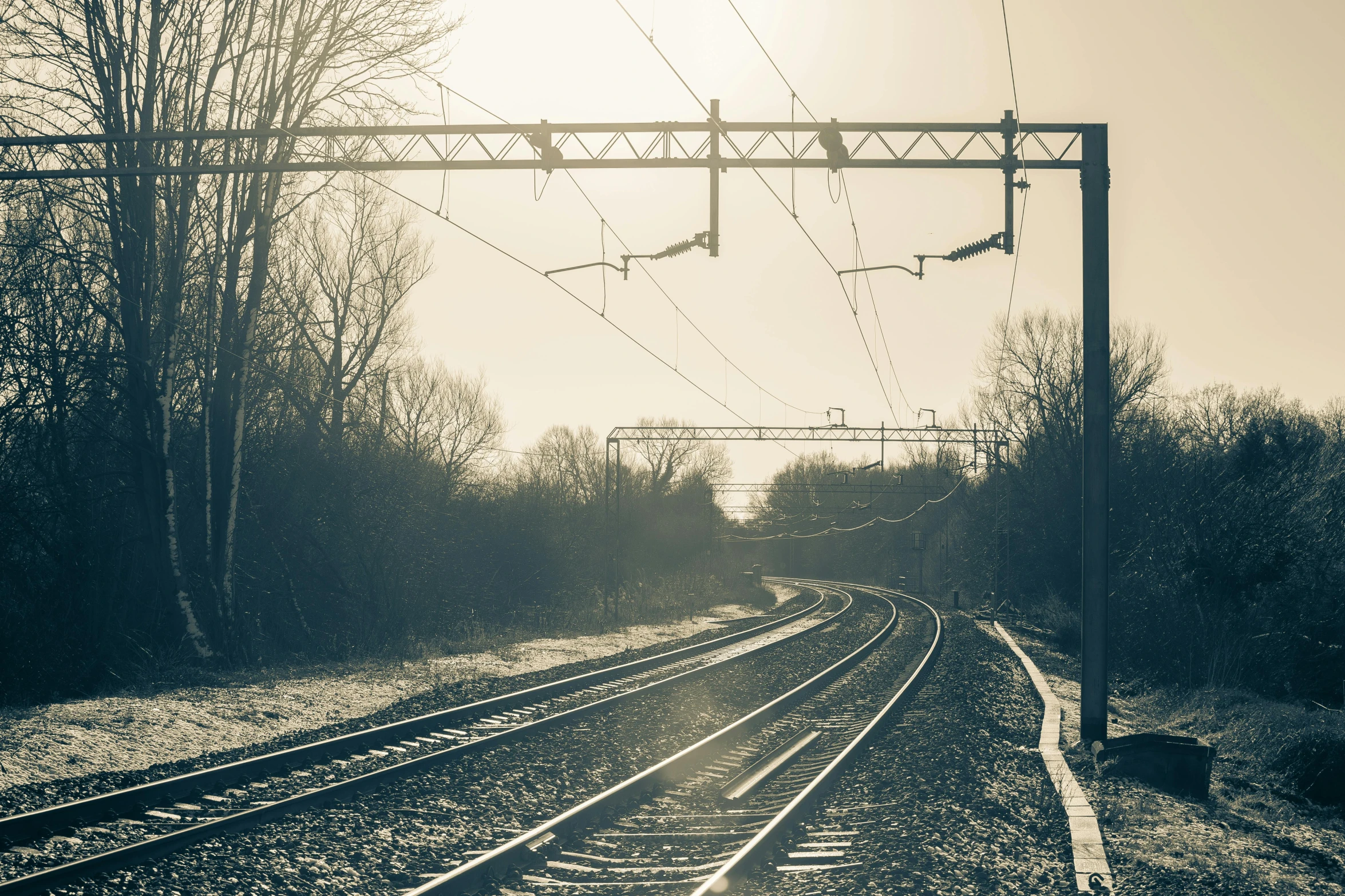 a black and white photo of a train track, by Lucia Peka, unsplash, sepia sunshine, winter photograph, suburban, early evening