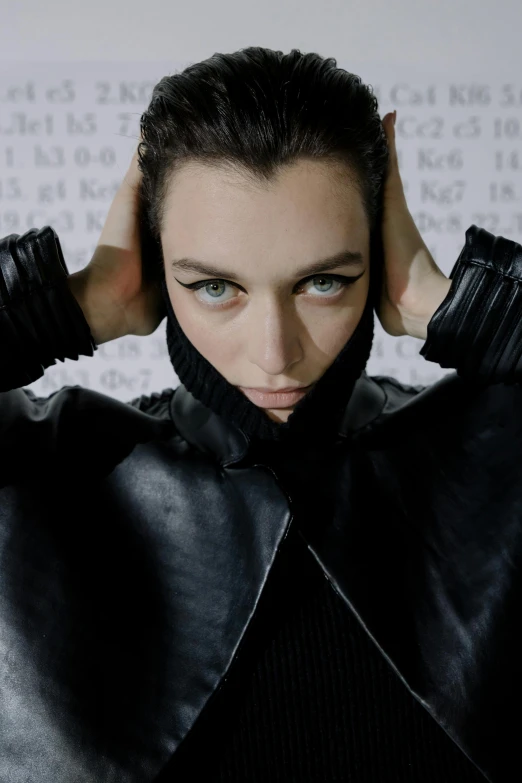 a woman in a black leather jacket with her hands on her head, an album cover, inspired by Peter Lindbergh, trending on pexels, antipodeans, iris van herpen, attractive androgynous humanoid, mandel eyes, bella hadid