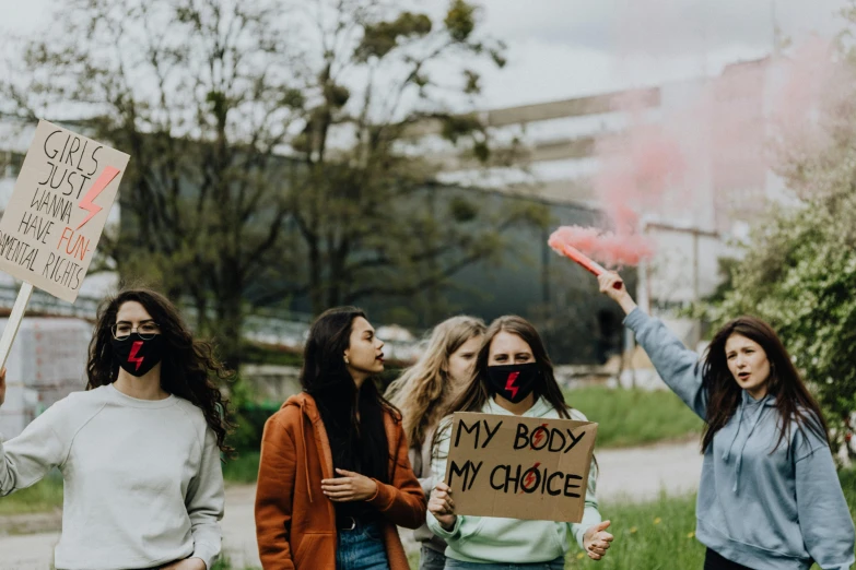 a group of women standing next to each other holding signs, by Emma Andijewska, pexels contest winner, teenager girl, smoke coming out of her mouth, on a canva, bodies