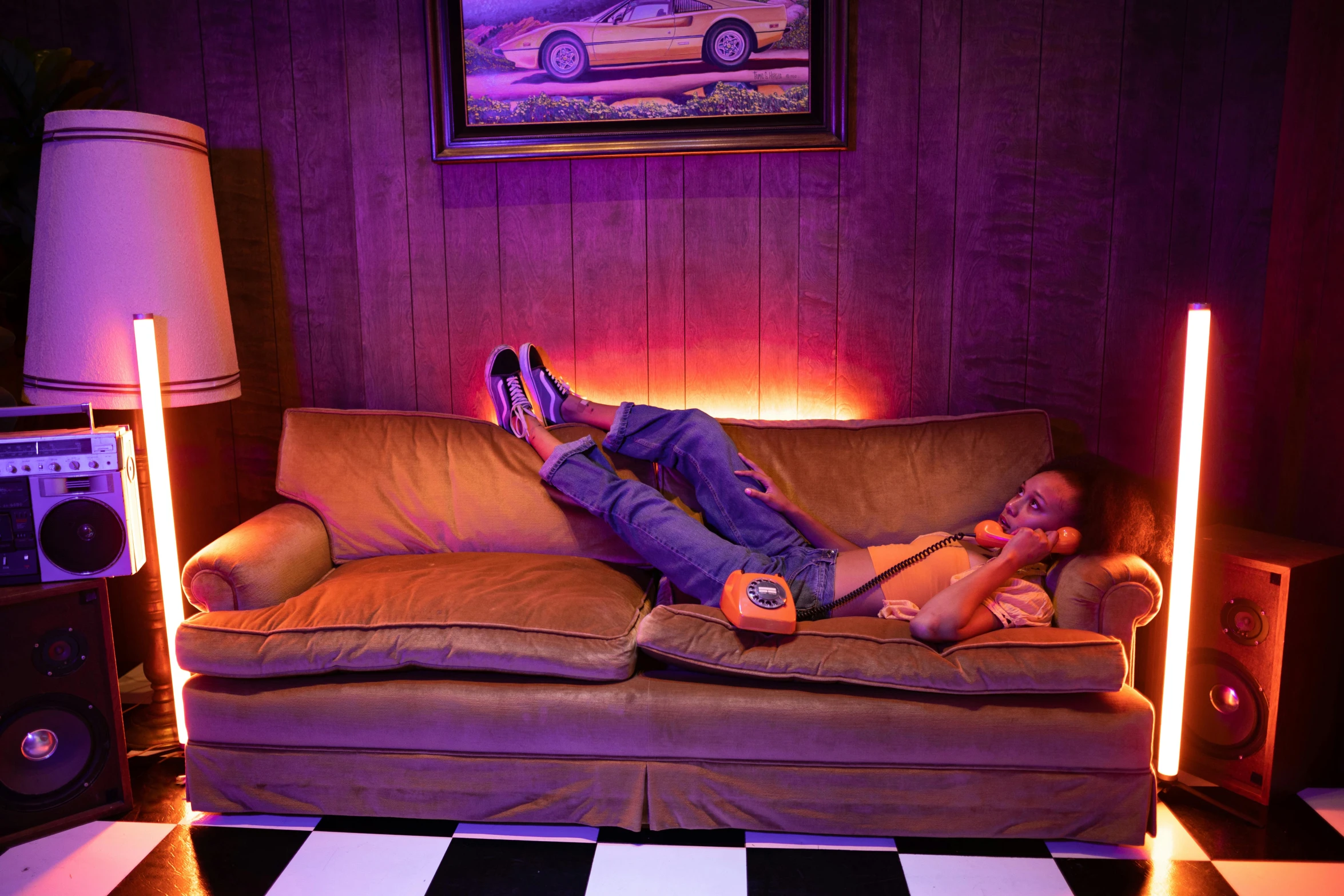 a man laying on top of a couch in a living room, inspired by Nan Goldin, maximalism, soft neon purple lighting, sports car in the room, 2019 trending photo, still from a wes anderson movie