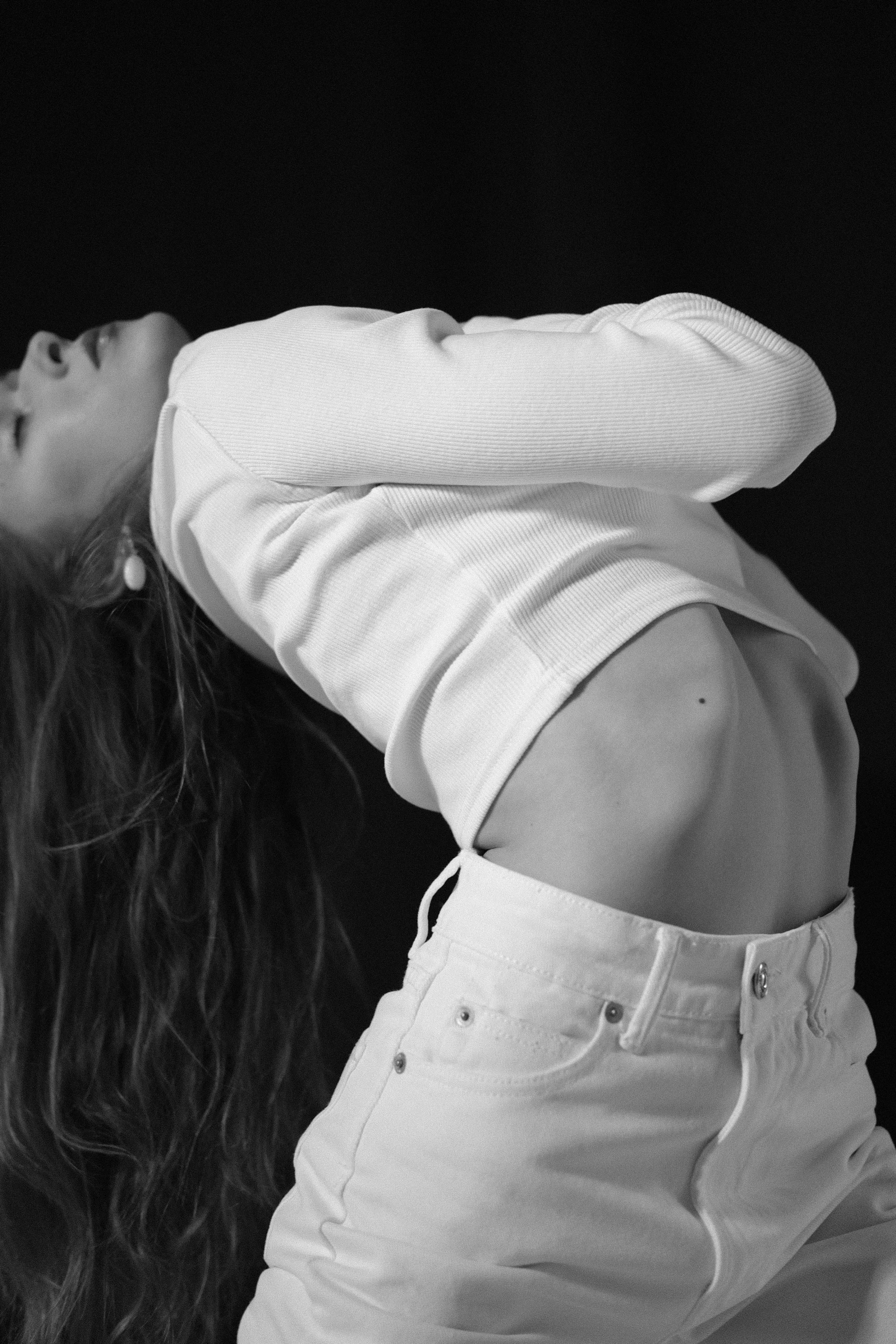 a black and white photo of a woman with long hair, a black and white photo, pexels contest winner, ripped up white garment, ( ( ( wearing jeans ) ) ), bella poarch, bend over posture