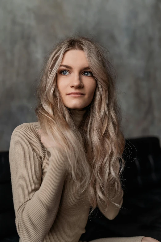 a woman sitting on top of a black couch, a portrait, inspired by Louisa Matthíasdóttir, trending on pexels, long ashy hair, full head shot, hair coloring, beige hair