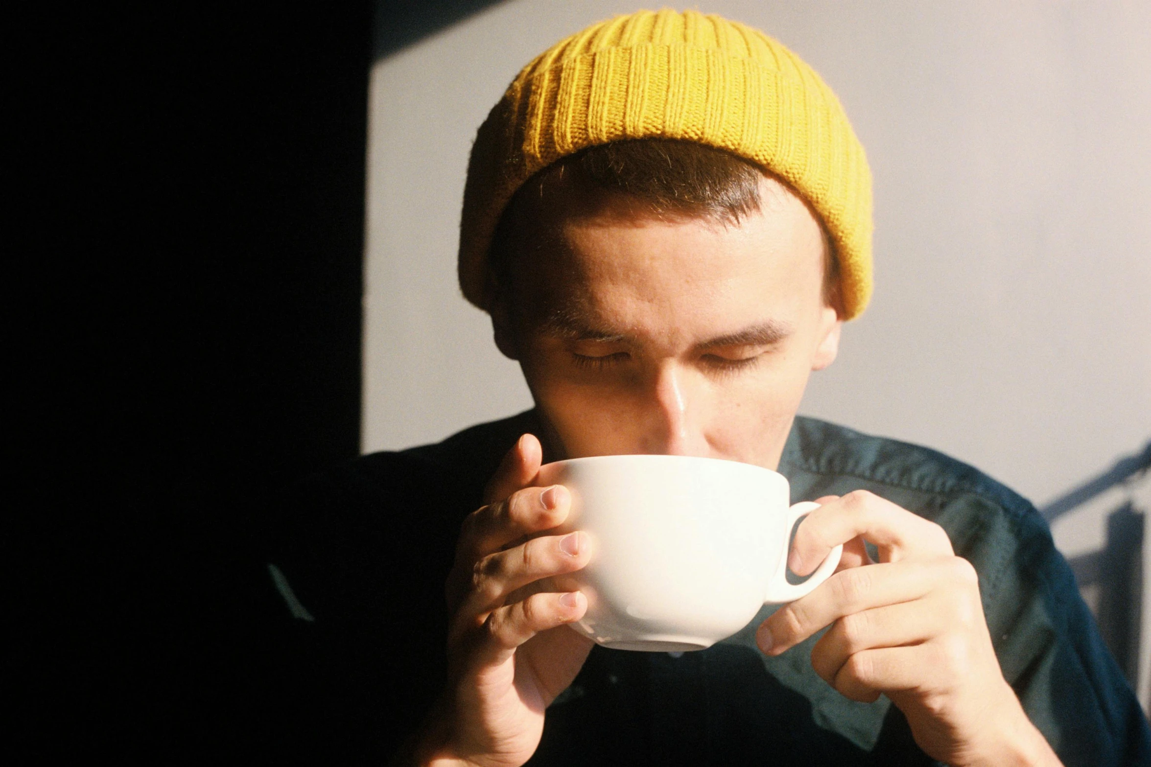 a man in a yellow hat drinking from a white cup, pexels contest winner, wearing beanie, secret tea society, aussie baristas, joe keery