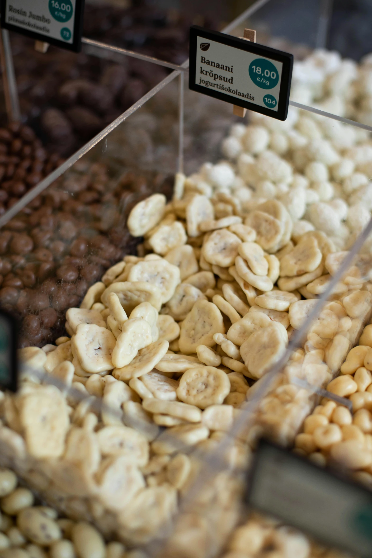 a display case filled with lots of different kinds of nuts, clumps of bananas, up close, chips, thumbnail