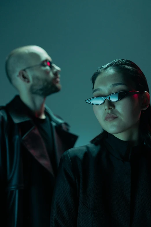 a man and a woman standing next to each other, an album cover, inspired by Wang Duo, unsplash, futurism, tech glasses, intense lighting, asian women, demna gvasalia