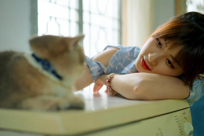 a woman laying on top of a counter next to a cat, trending on pexels, realism, young adorable korean face, shojo, blue, taken with sony alpha 9