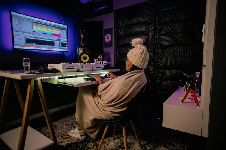 a person sitting at a desk in front of a computer, an album cover, pexels contest winner, studio room, purple ambient light, winter vibes, solo performance unreal engine