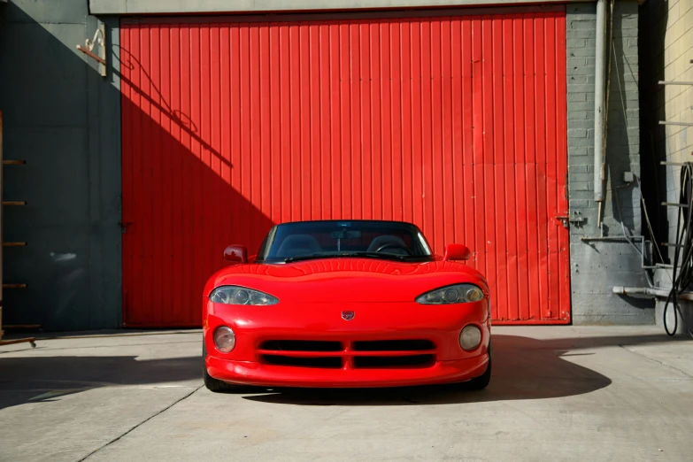 a red sports car parked in front of a garage, a portrait, unsplash, taken in 1 9 9 7, soft color dodge, dizzy viper, front