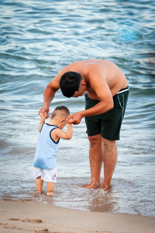 a man standing next to a child on a beach, incoherents, square, asian male, trending, brown