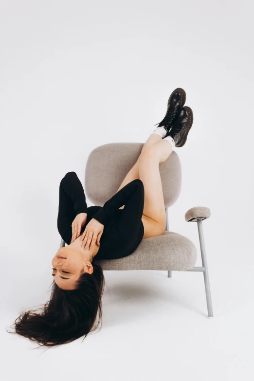 a woman laying on a chair with her legs up, inspired by Ion Andreescu, unsplash contest winner, set against a white background, madison beer, head tilted down, armchair