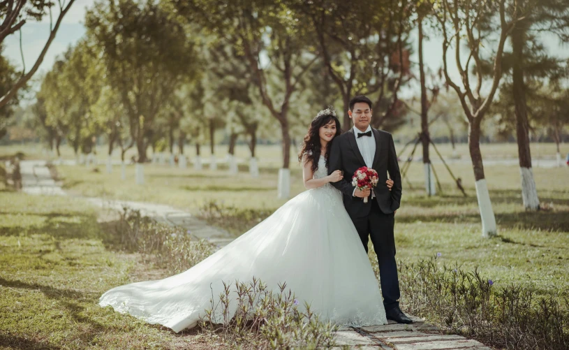 a man in a tuxedo standing next to a woman in a wedding dress, a picture, pexels contest winner, sunny environment, in style of lam manh, 15081959 21121991 01012000 4k, trees in the background