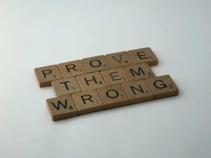 wooden scrabbles spelling prove them wrong, an album cover, by Steve Prescott, pexels contest winner, professional product photo, panel, white, 3 4 5 3 1