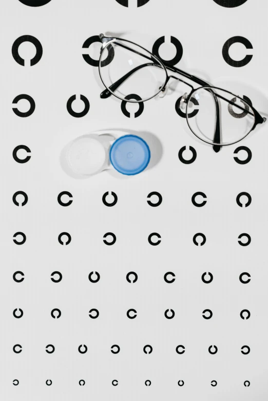 a pair of glasses sitting on top of an eye chart, an album cover, inspired by Leo Leuppi, trending on pexels, optical illusion, light blue piercing eyes, circles, healthcare, panels