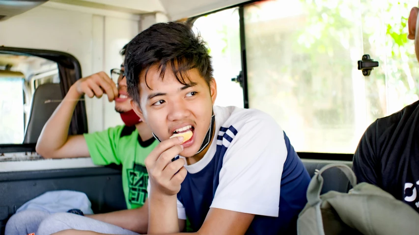 two men sitting in the back of a van eating food, pexels contest winner, sumatraism, chewing on a graphic card, teenager, slightly smiling, asher duran